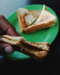 Close-up of hand holding bread in plate