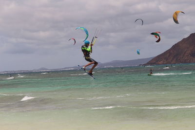 People flying over sea against sky