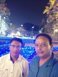 Portrait of friends against illuminated blue sky at night