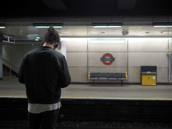 Rear view of man standing at railroad station