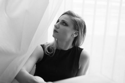 Beautiful woman looking up while sitting on bed