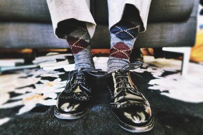 Low section of man wearing dress shoe on rug