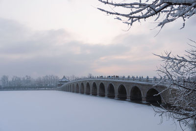 Bridge over river against sky during winter