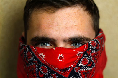 Young man in red bandana. closeup blue dark eyes. man with his face hidden behind a bandanna stares