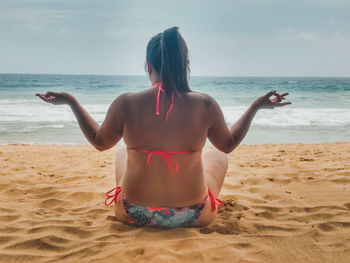 Rear view of man on beach against sky