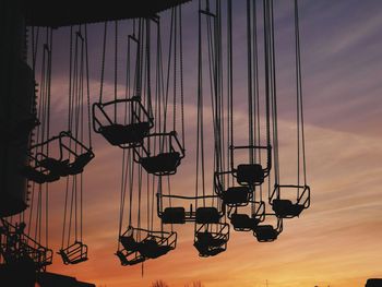 Low angle view of silhouette chain swing ride against sky