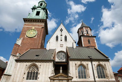 Low angle view of clock tower amidst buildings against sky