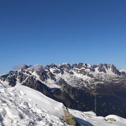 Scenic view of snowcapped mountains against clear blue sky