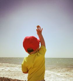 Boy standing on beach against clear sky