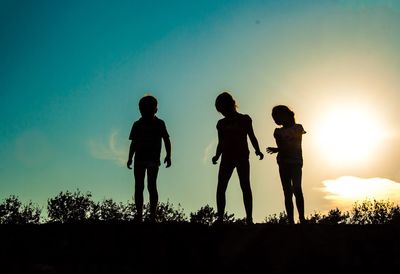 Friends standing on field at sunset