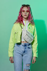 Portrait of young woman standing against blue background