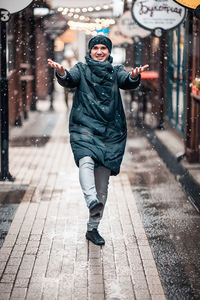 Full length portrait of woman standing on footpath during winter