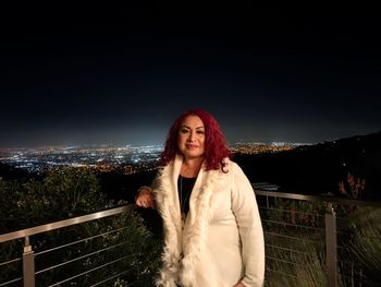 Portrait of beautiful woman standing against sky at night