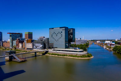 River by modern buildings against clear blue sky