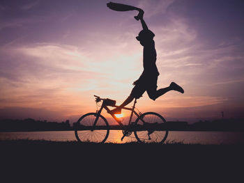 Silhouette bicycle on beach against sky during sunset