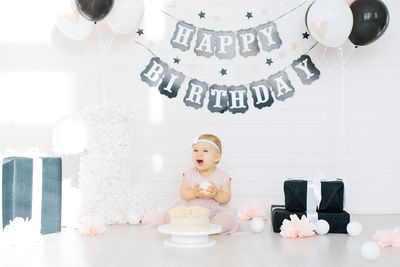 Birthday girl 1 year old sitting in the photo zone near the birthday cake
