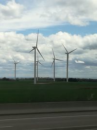 Windmills on field against sky