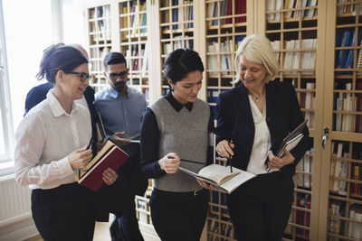 Smiling lawyers discussing while walking by bookshelf in library