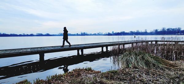 Woman standing by lake against sky