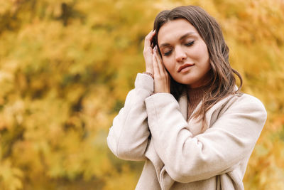 A beautiful happy girl in casual clothes is walking in the autumn outdoor park drinking coffee