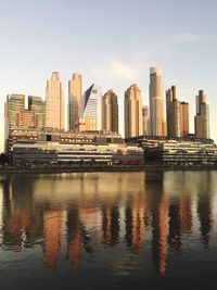 Modern buildings by river against sky in city