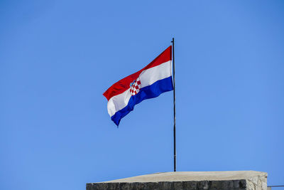 Low angle view of flags flag against clear blue sky