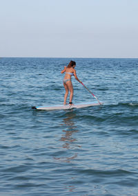 Full length of woman on surf in sea against sky