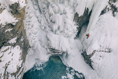 High angle view of woman climbing on snowcapped mountain during winter