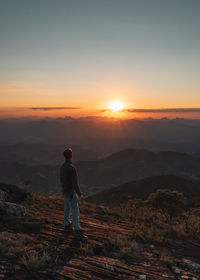 Man standing on mountain against sky during sunset