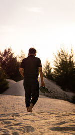 Rear view of man on beach during sunset