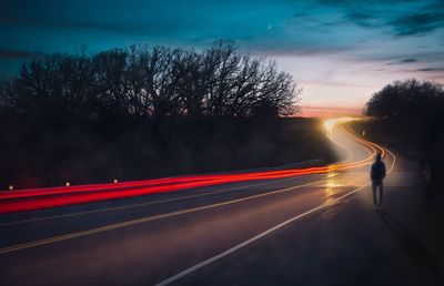 Light trails on road against sky at night