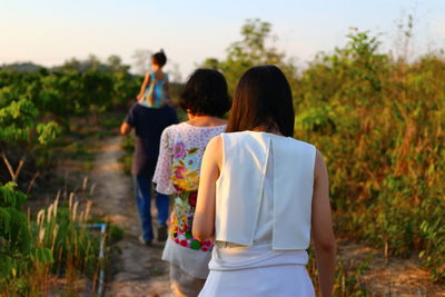 Rear view of family walking in field