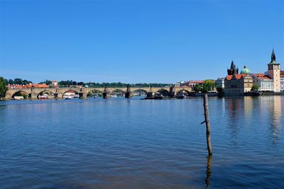 Scenic view of river by buildings against clear blue sky