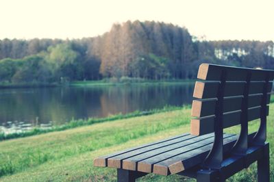 View of park bench by lake against sky