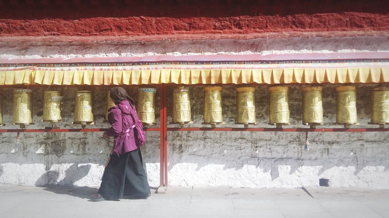 real people, one person, full length, architecture, built structure, women, standing, clothing, adult, day, side view, pink color, walking, building, lifestyles, indoors, traditional clothing, in a row, warm clothing