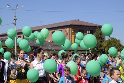 Group of people at balloons against blue sky