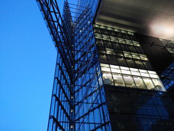 Low angle view of illuminated modern building against clear blue sky