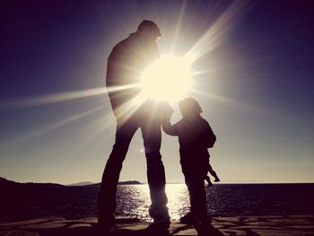 Silhouette of people standing on beach at sunset