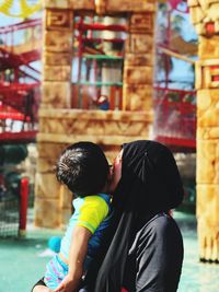 Side view of mother kissing son at playground