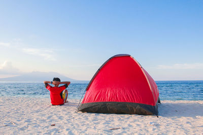 Red umbrella on beach against sky