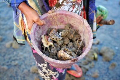 Low section of woman holding a bucket of clams 