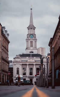 Buildings in city against cloudy sky