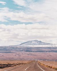 Road leading towards mountains against sky