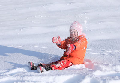 Cheerful girl sitting on snowy land