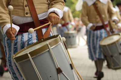 Midsection of people playing drum on street 