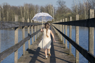 Portrait of girl with umbrella walking over water