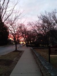 Street amidst trees against sky during sunset