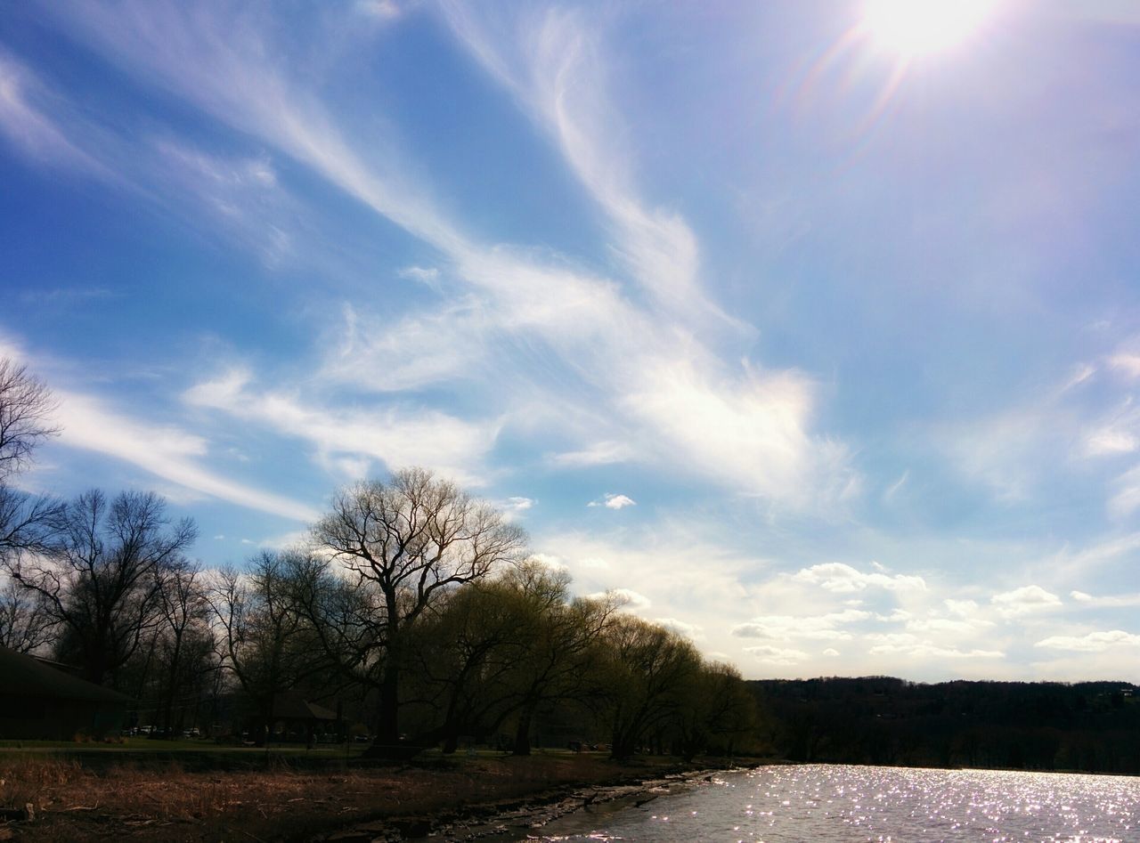 water, tree, sky, tranquility, tranquil scene, beauty in nature, scenics, sunlight, river, nature, cloud - sky, sun, lake, bare tree, sunbeam, reflection, cloud, silhouette, waterfront, outdoors