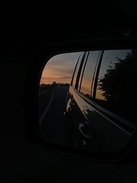 Reflection of sky on side-view mirror at sunset