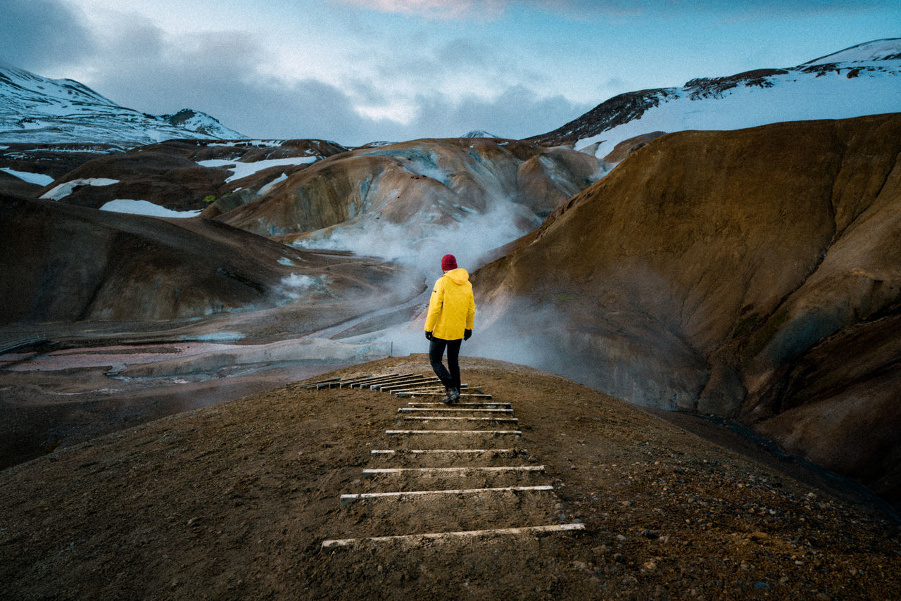 one person, full length, rear view, mountain, real people, lifestyles, leisure activity, cloud - sky, standing, sky, beauty in nature, scenics - nature, non-urban scene, nature, day, travel, adult, tranquility, vacations, outdoors, warm clothing